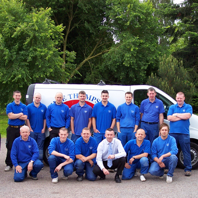 The Mike Thompson Electrical team in matching blue polo shirts, standing and kneeling in front of a liveried company van