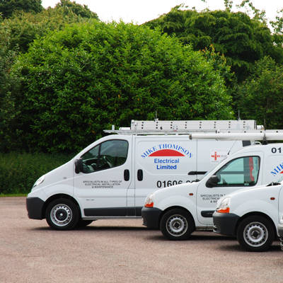 Three white Mike Thompson Electrical Limited vans in their red and navy livery, parked in a row